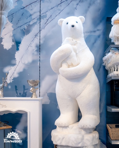 Ours polaire en peluche tenant un ourson dans un décor hivernal magique.